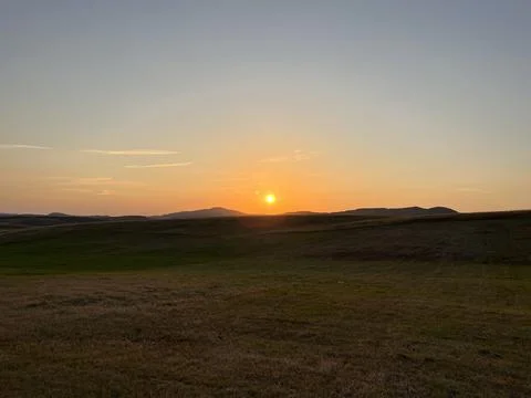 Sun Setting Over Hills and Field, Dramatic Orange Sky Stock Photos