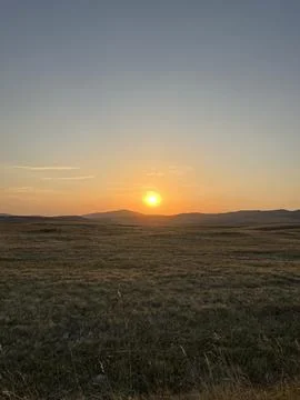 Sun Setting Over Hills and Field, Dramatic Orange Sky Stock-Fotos