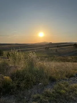 Sun Setting Over Hills and Field, Dramatic Orange Sky Stock-Fotos