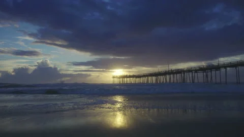 Sun setting over jetty next to beach at Cape Hatteras Stock Footage 311645709