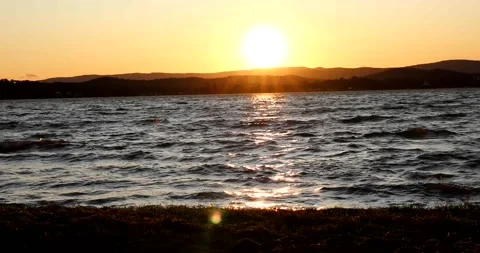 Sun setting over the lake behind the mountains Stock Footage 211070009