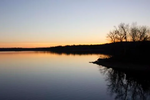 Sun setting over lake with reflection Stock Photos