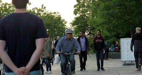Sun setting over Manhattan Battery Park with pedestrians and bikers passing by Stock Footage 77258556