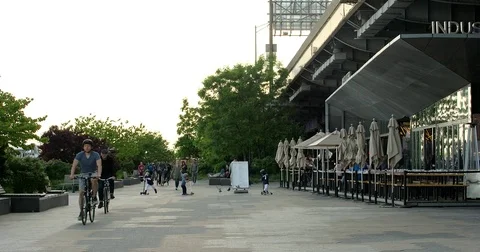 Sun setting over Manhattan Battery Park with pedestrians and bikers passing by Stock Footage 77259134