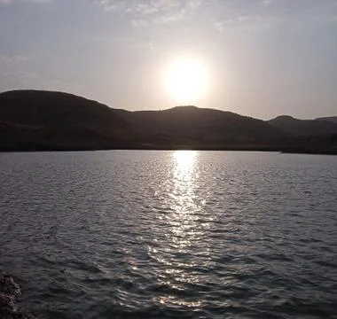 Sun setting over the mountain lake Stock Photos
