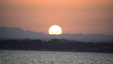 Sun setting over the mountains against seascape. 库存影片 112973961