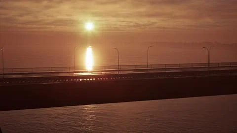 Sun Setting Over Ocean With Bridge in Foreground Stock Illustration