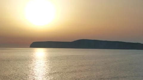 The sun is setting over the ocean, casting a warm glow on the water Stock Footage 298250611