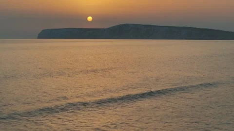 The sun is setting over the ocean, casting a warm glow on the water Stock Footage 298250926