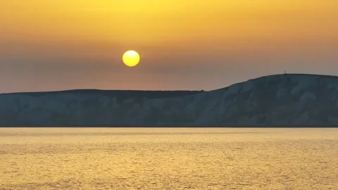 The sun is setting over the ocean, casting a warm glow over the water Stock Footage 298250942