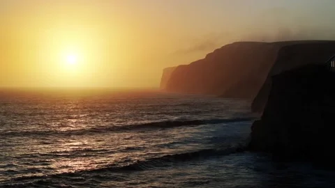 The sun is setting over the ocean, casting a warm glow on the water Stock Footage 303710055