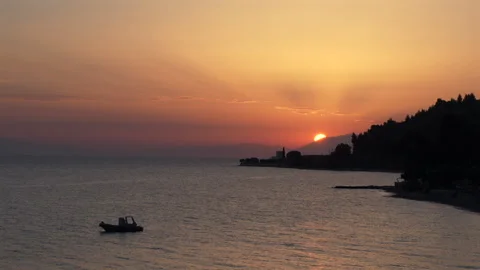 The sun is setting over the ocean, casting a warm orange glow over the water 库存影片 319017632