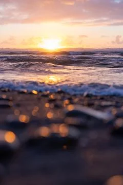 The sun is setting over the ocean, casting a warm glow on the water Stock Photos