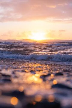 The sun is setting over the ocean, casting a warm glow on the water Stock Photos