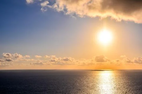 The sun is setting over the ocean, casting a warm glow on the water Stock-Fotos