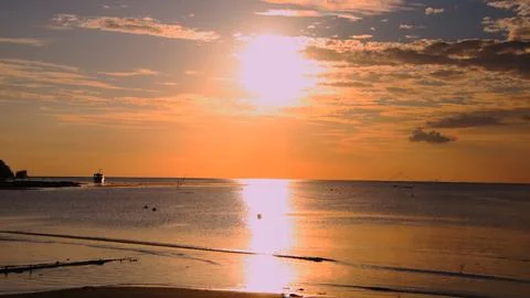 The sun is setting over the ocean, casting a warm glow on the water Stock Photos