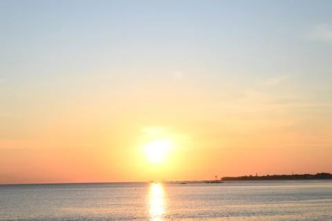 The sun is setting over the ocean, casting a warm glow over the water Stock Photos