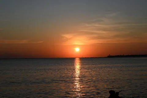 The sun is setting over the ocean, casting a warm glow on the water Stock Photos