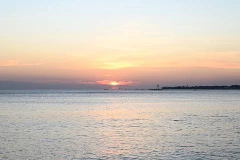 The sun is setting over the ocean, casting a warm glow on the water Stock Photos