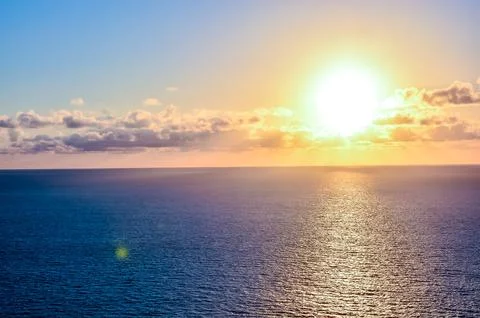 The sun is setting over the ocean, casting a warm glow on the water Stock Photos