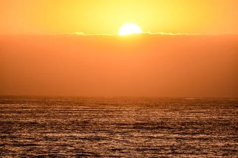 The sun is setting over the ocean, casting a warm glow on the water Foto stock