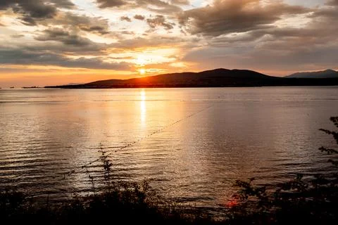 The sun is setting over the ocean, casting a warm glow on the water Stock Photos