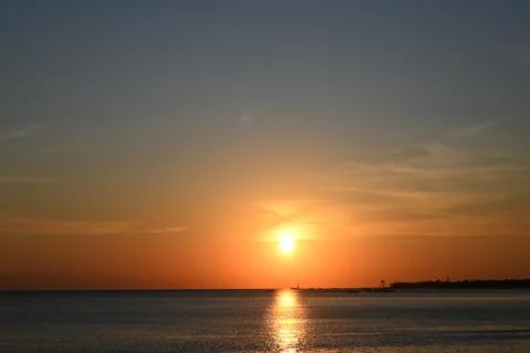 The sun is setting over the ocean, creating a beautiful and serene atmosphere Stock Photos