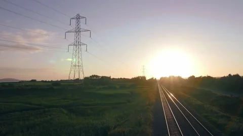Sun setting over rail line and pylon Stock Footage 66777581