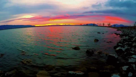 The sun is setting over a river lined with trees, creating a beautiful natural l Stock Footage 276607749