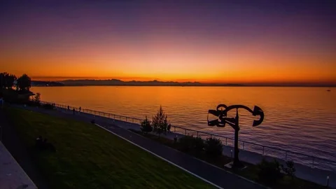 The sun is setting over a river lined with trees, creating a beautiful natural l Stock Footage 276630931