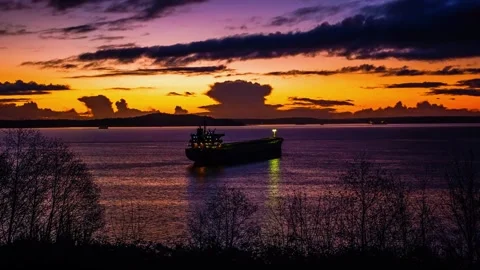 The sun is setting over a river lined with trees, creating a beautiful natural l Stock Footage 276630959