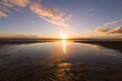 Sun setting over sandy beach Stock Photos