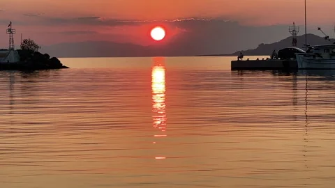 The sun is setting over the sea, creating a beautiful orange and pink sky Stock Footage 322900472