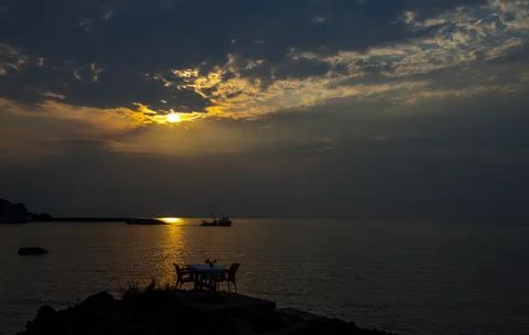 The sun is setting over the sea. Reflection. silhouettes. Waves in the sea. Stock Photos
