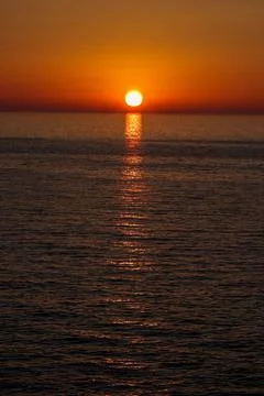 The sun is setting over the sea. Reflection. silhouettes. Waves in the sea. Stock Photos