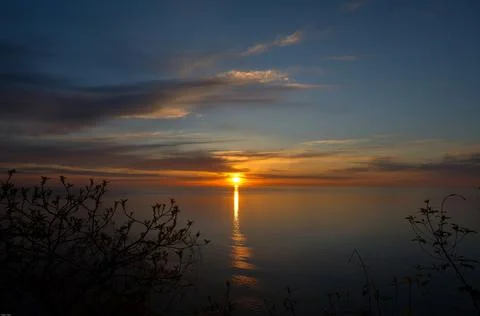 The sun is setting over the sea. Reflection. silhouettes. Waves in the sea. Stock Photos