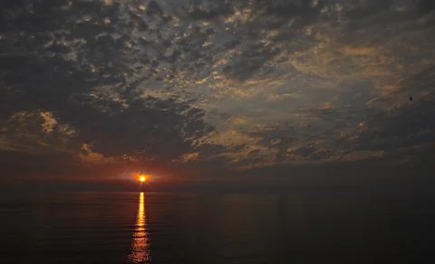 The sun is setting over the sea. Reflection. silhouettes. Waves in the sea. Stock Photos