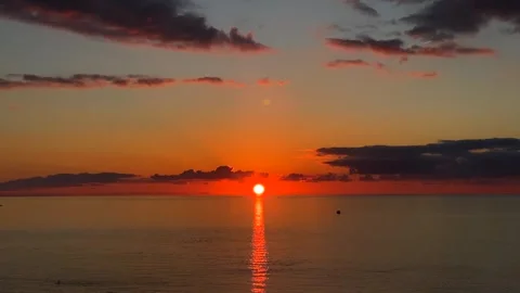 Sun setting over sea, wide view of a glowing horizon with dark clouds Stock Footage 345361892