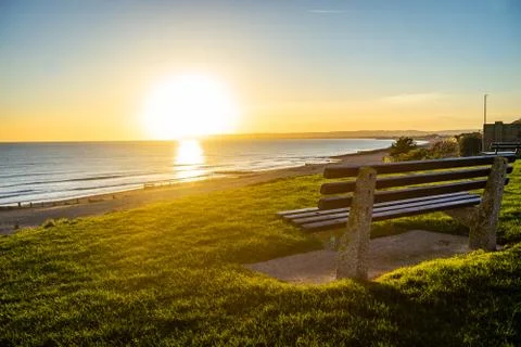 Sun setting over seaside bench Stock Photos