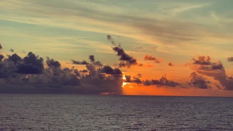 Sun setting over a vast ocean with dark clouds and orange sky creating a dr.. Stock Footage 338282630