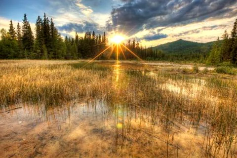 The sun setting over the warm streams around the Liard Hotsprings in northern Stock Photos