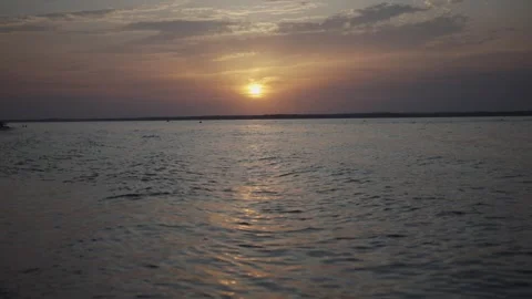 The sun is setting over the water, creating a beautiful and serene atmosphere Stock Footage 297886712