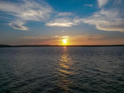 The sun is setting over the water, creating a beautiful and serene atmosphere Stock Photos