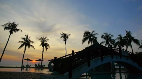 Sun setting reflected in pool water under the palm trees in a tropical resort Stock Footage 60259763