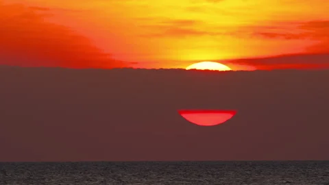 Sun setting into sea horizon during dramatic red sunset timelapse Stock Footage 345363758