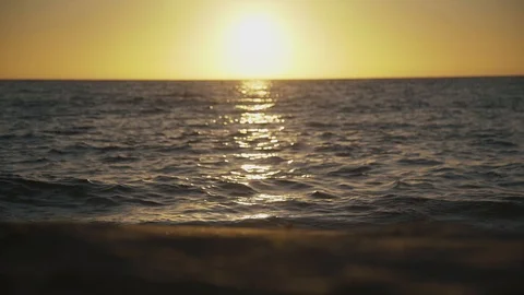 Sun setting at the sea reflecting on the beach and water surface Stock Footage 125213921