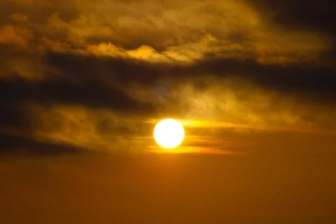 The sun is setting in the sky with the sun shining through the clouds. Foto stock