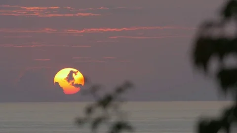 Sun setting slowly on the horizon of a water body Stock Footage 77559010