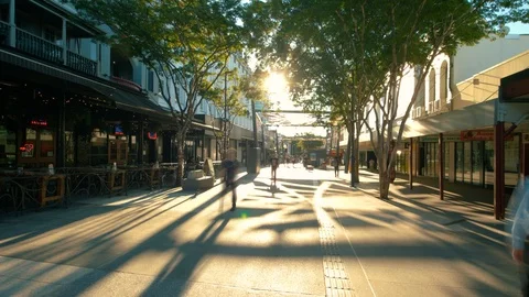 Sun setting through trees over bars and busy street Stock Footage 86931171
