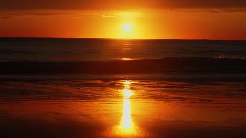 Sun setting with waves breaking on shore Stock Footage 260370048